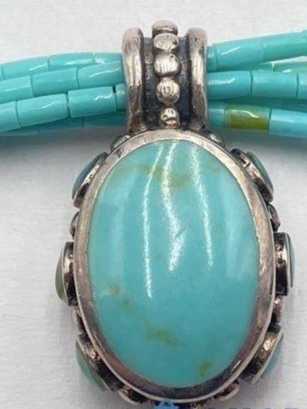 multi-strand turquoise bead necklace w/silver pendant w/a central stone